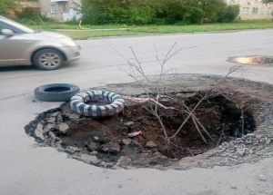 Огромная яма образовалась на Филатова. Местные накидали ветки и покрышки,...