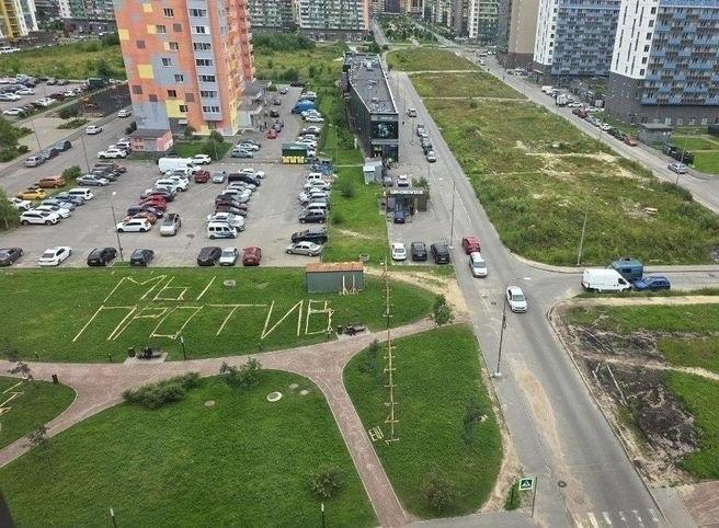 Такую надпись из досок выложили на зеленой поляне в Мурино энтузиасты,...